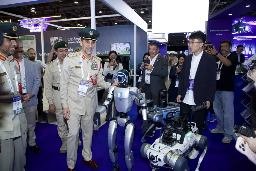 Dubai Police officers viewing a humanoid robot on the exhibition floor